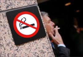 Man smoking next to a non smoking sign